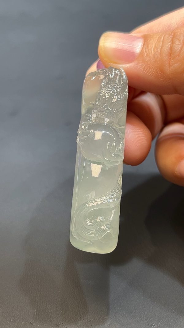 這款天然A級翡翠龍戲珠吊墜（編號#256），以細膩通透的翡翠雕刻而成，呈現祥龍翻騰戲珠的生動場景，氣勢磅礡、栩栩如生。龍象徵權威與吉運，戲珠寓意智慧與圓滿，整體設計蘊含祥瑞之意。佩戴此吊墜，不僅彰顯品味，更寓意事業飛騰、福氣盈門。