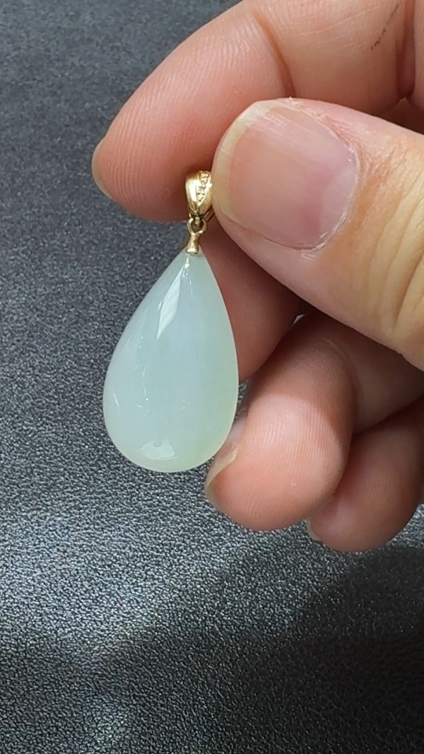 直播貨品編號 #338 的18K鑲嵌白色水滴吊墜，外型如初雪凝露，展現簡潔雅致的高冷美感。水滴造型柔和靈動，寓意純淨心念與堅韌精神；白色翡翠質地通透細膩，在燈光映照下泛出柔潤光澤，猶如心湖微波，靜中藏韻。周邊由18K金優雅包邊，線條流暢，既穩固又增添光澤，完美融合古典玉石與現代設計。