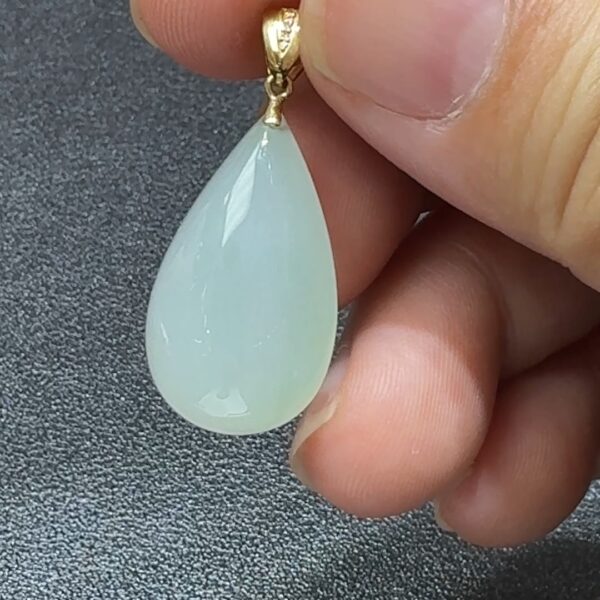直播貨品編號 #338 的18K鑲嵌白色水滴吊墜，外型如初雪凝露，展現簡潔雅致的高冷美感。水滴造型柔和靈動，寓意純淨心念與堅韌精神；白色翡翠質地通透細膩，在燈光映照下泛出柔潤光澤，猶如心湖微波，靜中藏韻。周邊由18K金優雅包邊，線條流暢，既穩固又增添光澤，完美融合古典玉石與現代設計。